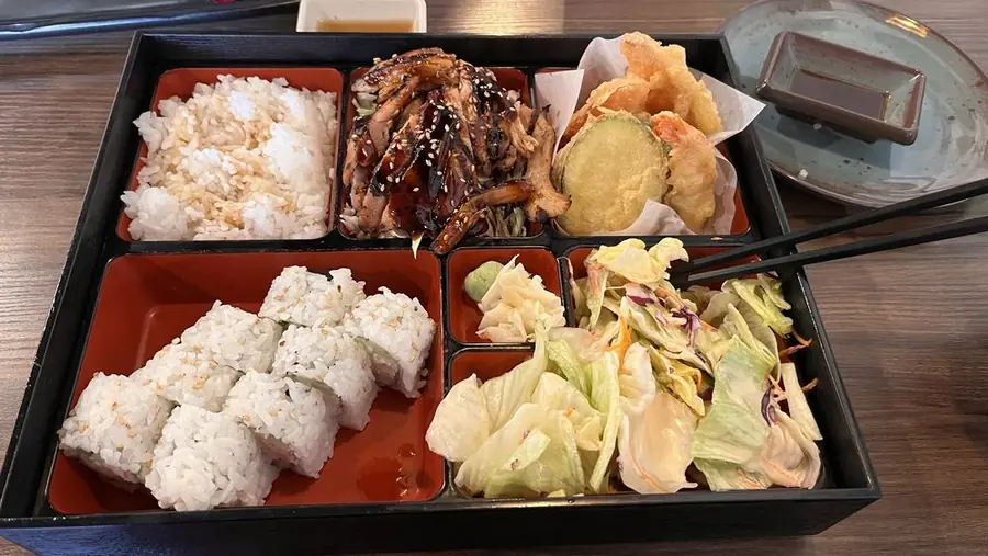 A bento box with rice, tempura, teriyaki and salad